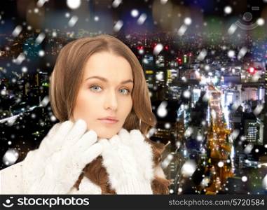 happiness, winter holidays, christmas and people concept - smiling young woman in white warm clothes over snowy city background