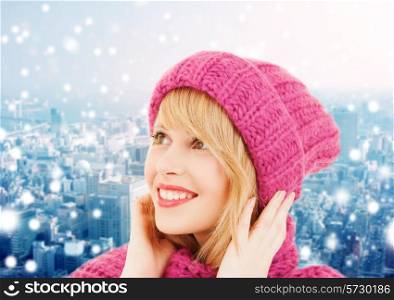 happiness, winter holidays, christmas and people concept - smiling young woman in pink hat and scarf over blue snowy background
