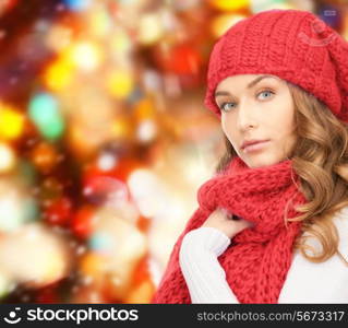 happiness, winter holidays, christmas and people concept - young woman in hat and scarf over red lights background