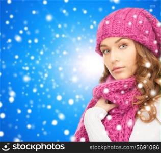 happiness, winter holidays, christmas and people concept - young woman in pink hat and scarf over blue snowy background