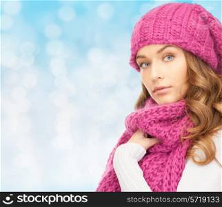 happiness, winter holidays, christmas and people concept - young woman in pink hat and scarf over blue lights background