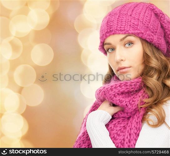 happiness, winter holidays, christmas and people concept - young woman in pink hat and scarf over beige lights background