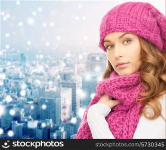 happiness, winter holidays, christmas and people concept - young woman in pink hat and scarf over blue snowy background