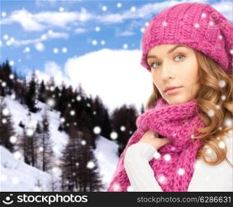 happiness, winter holidays, christmas and people concept - young woman in pink hat and scarf over snowy mountains background