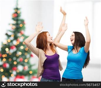 happiness, winter holidays, friendship and people concept - smiling teenage girls having fun over living room and christmas tree background