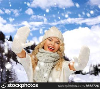 happiness, winter holidays, tourism, travel and people concept - smiling young woman in white hat and mittens over snowy mountains background