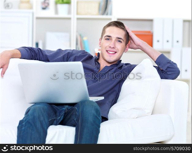 happiness young man with laptop and lying on the sofa