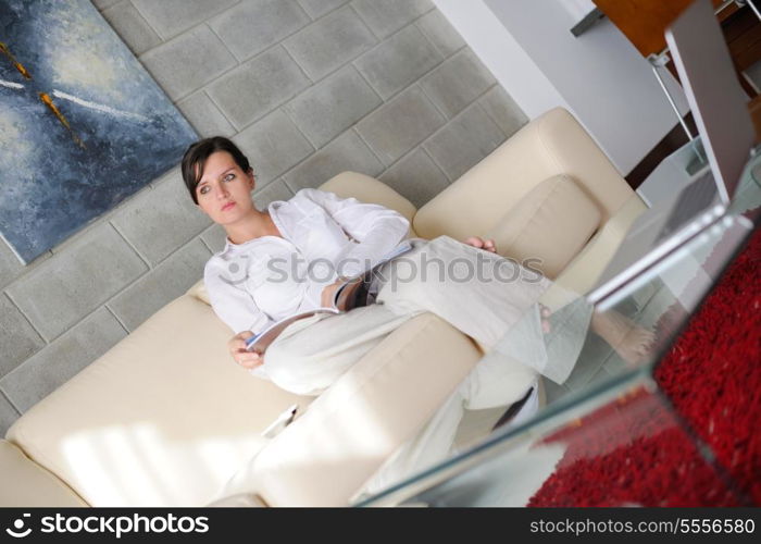 happpy young woman reading magazina at home in comfortabel sofa and bright living room