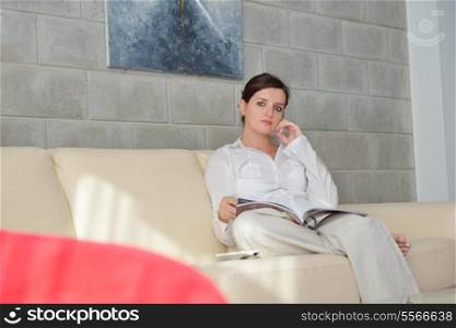 happpy young woman reading magazina at home in comfortabel sofa and bright living room