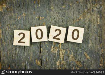 Happy 2020 new year. Numbers, typography on wooden blocks over wood texture background, flat lay style. Two thousand twenty holiday and celebration concepts