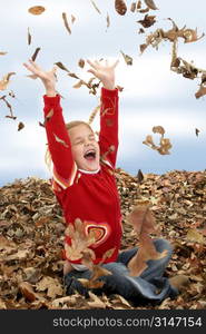 Happy 7 year old girl playing in a big pile of dried leaves. Shot in studio over white.