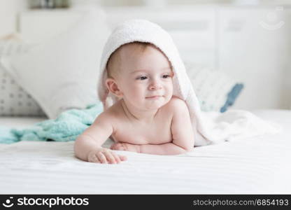 Happy 9 months old baby looking under towel after having bath