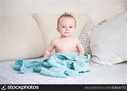 Happy 9 months old baby on bed after bathing