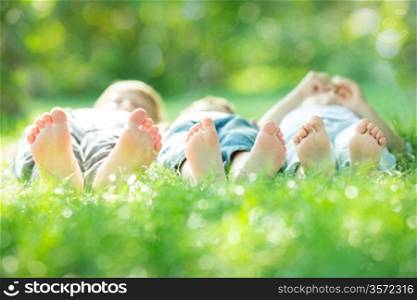 Happy active family lying on green grass in spring park
