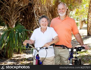 Happy active senior couple enjoys bicycling together.