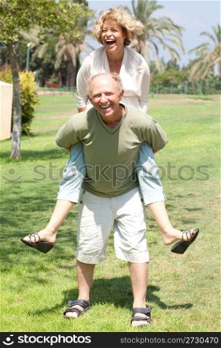 Happy active senior man giving woman piggyback ride