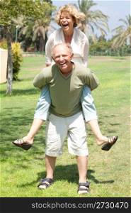 Happy active senior man giving woman piggyback ride