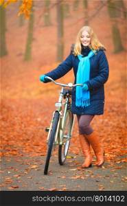 Happy active woman riding bike in autumn park.. Happy active woman riding bike bicycle in fall autumn park. Glad young girl in jacket and scarf relaxing. Healthy lifestyle and recreation leisure activity.