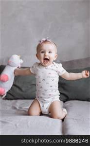 happy adorable little girl is playing with toy unicorn on bed at home. concept of childhood day. happy baby’s, family day.. happy adorable little girl is playing with toy unicorn on bed at home. concept of childhood day. happy baby’s, family day