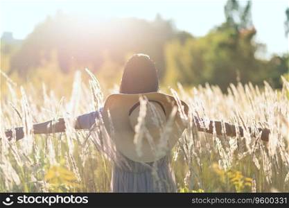 Happy adult woman at summer meadow in a sunset light, chilling outdoor, blurred defocused lifestyle portrait with backlighting haze and plant pollen and dust in air, back view, summer vacation concept. Happy adult woman at summer meadow in sunset light, chilling outdoor, blurred defocused lifestyle portrait with backlighting haze and plant pollen and dust in air, back view, summer vacation concept