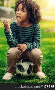 Happy african american child eating snack stick in the park. Children nutrition concept.