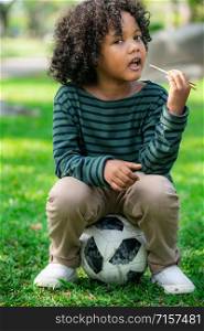 Happy african american child eating snack stick in the park. Children nutrition concept.
