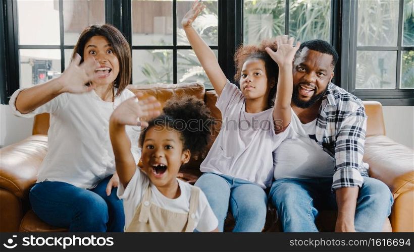 Happy African American family dad, mom and daughter having fun cuddle and video call on laptop on sofa at house. Self-isolation, stay at home, social distancing, quarantine for coronavirus prevention.