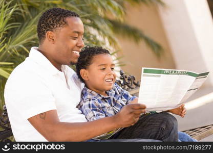 Happy African American Father and Mixed Race Son Having Fun Reading Park Brochure Outside.