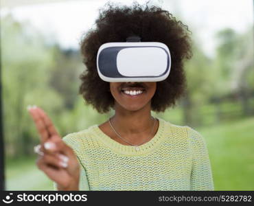 Happy african american girl getting experience using VR headset glasses of virtual reality at home