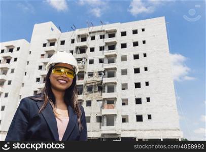 happy african american lady safety helmet eyeglasses near building construction