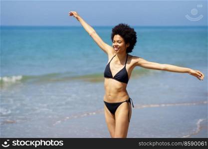 Happy African American woman opening her arms on the beach to enjoy her holiday in the sun.. Happy black woman opening her arms on the beach to enjoy her holiday in the sun.