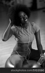happy african american woman with a curly afro hairstyle in a gym relaxing after pilates workout