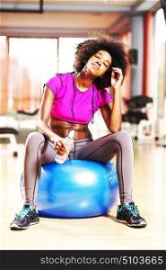 happy african american woman with a curly afro hairstyle in a gym relaxing after pilates workout