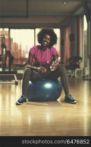 happy african american woman with a curly afro hairstyle in a gym relaxing after pilates workout. woman relaxing after pilates workout