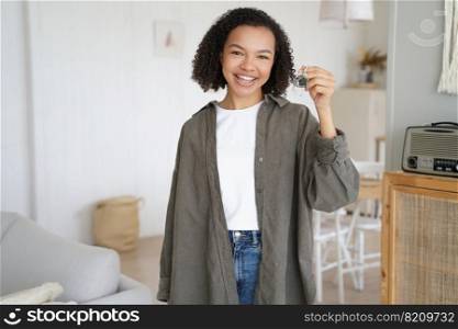 Happy african american young girl show keys to first own apartment. Smiling biracial teen lady holding house key, standing in new home. Real estate rental service advertising, relocation.. Happy african american young girl show keys to new home. Real estate rental service, relocation