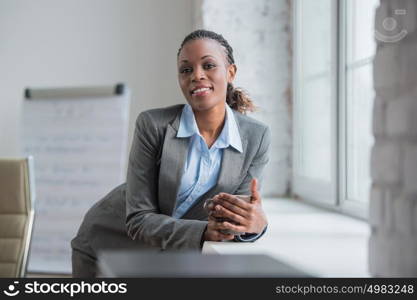 Happy african business woman enjoying the coffee break at her office and looking at window