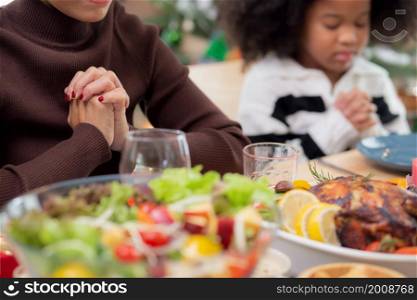 Happy African family holding hands and praying dinner on thanksgiving eve day together, merry Christmas, celebration and festive on food table, relationship of family, indoor, new year and xmas.
