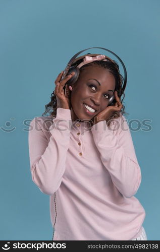 Happy African Woman listening to music on headphones. Young fresh African female model on blue background.