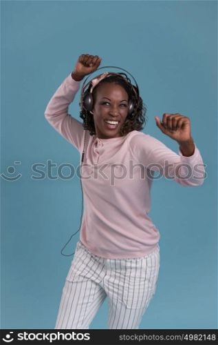 Happy African Woman listening to music on headphones. Young fresh African female model on blue background.