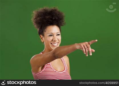 Happy African woman pointing to something over a green background