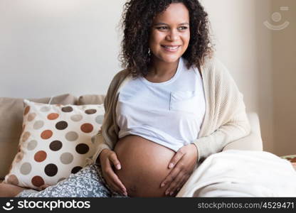 Happy afro woman showing her pregnant belly