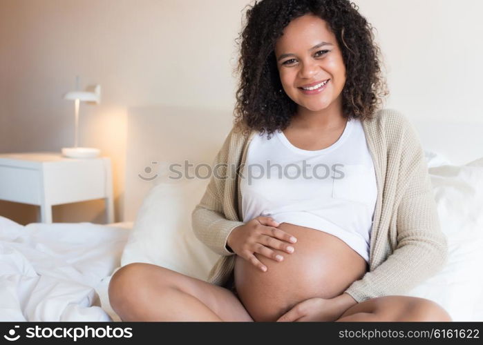 Happy afro woman showing her pregnant belly