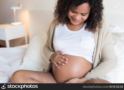 Happy afro woman showing her pregnant belly