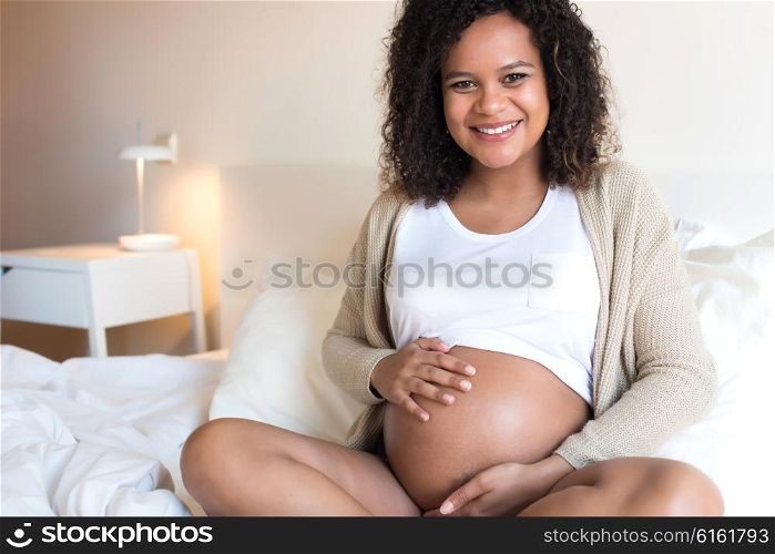 Happy afro woman showing her pregnant belly