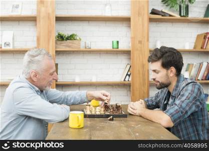 happy aged man young guy playing chess table room