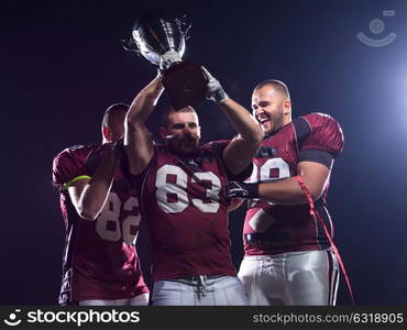 happy american football team with trophy celebrating victory on night field