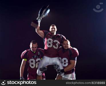 happy american football team with trophy celebrating victory on night field