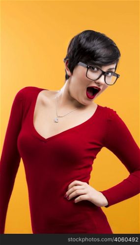 Happy and beautiful girl wearing nerd glasses, aganist a yellow background