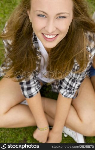 Happy and beautiful teenage girl sitting on the grass