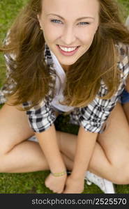 Happy and beautiful teenage girl sitting on the grass